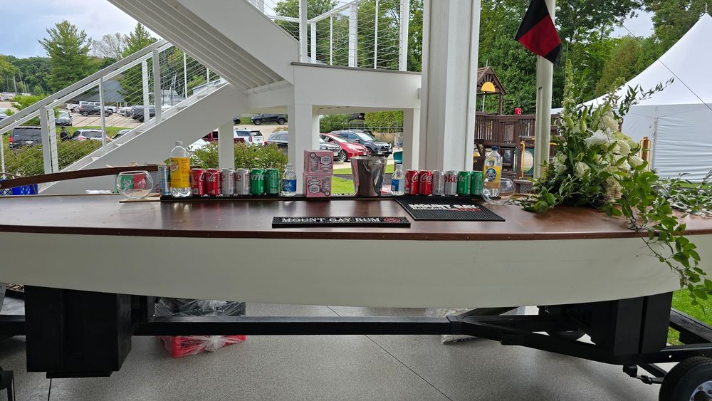 Outdoor bar setup with colorful canned drinks displayed on a boat-shaped counter at a summer event.