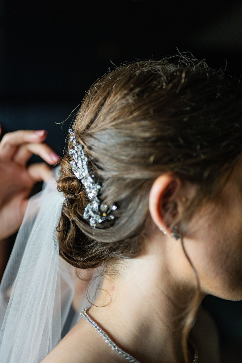Close-up of bride's elegant updo with sparkling crystal hair comb and delicate veil on wedding day.