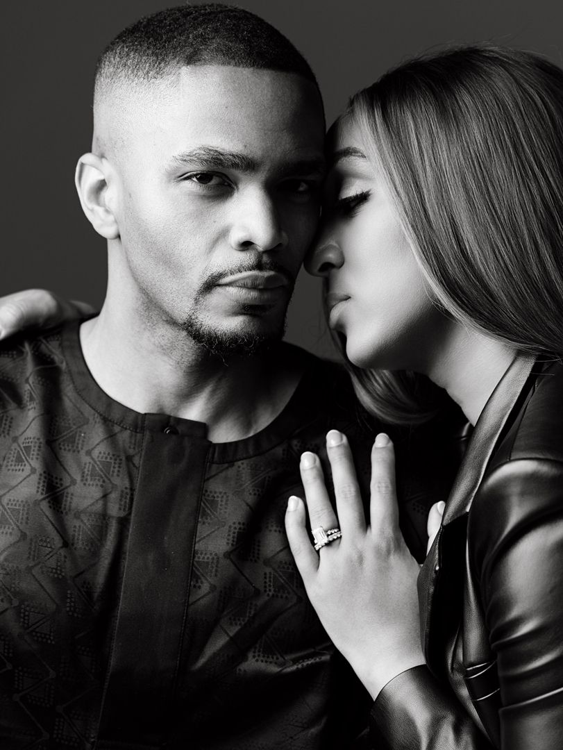 Black and white portrait of a couple, woman kissing man's cheek while showing diamond engagement ring.