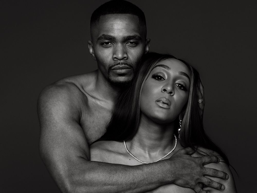 Black and white portrait of a shirtless man embracing a woman in a elegant studio photo shoot.