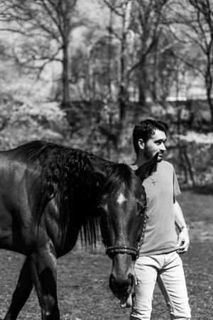 Black and white photo series of a couple with their horse in a natural outdoor setting.