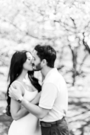 Soft focus romantic portraits of a couple embracing under spring blossoms.