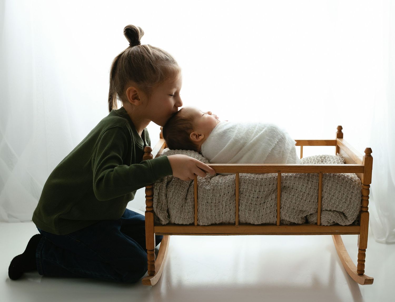 Big brother is kissing newborn brother's head in a cradle. - Greenville, SC newborn photographer - Easley, SC newborn photographer.