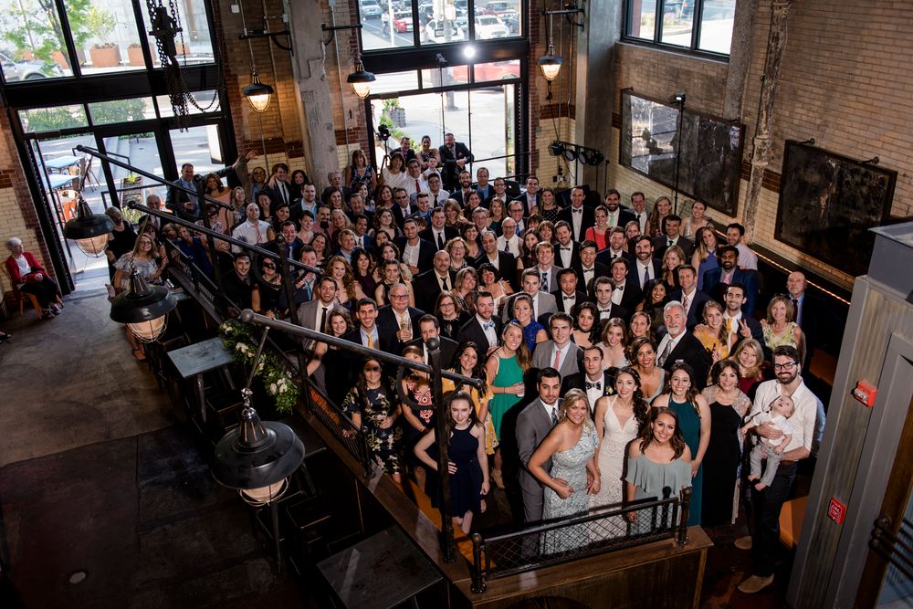 Large crowd of people gathered inside an industrial-style venue with exposed brick walls and windows during an event.