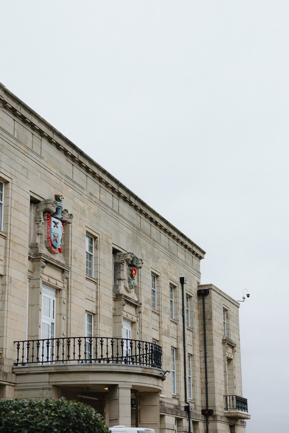 A classic stone building with balconies and decorative architectural details against a light gray sky.