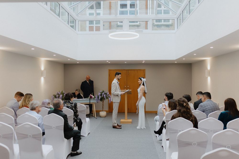 Modern white ceremony space with rows of chairs set up for a wedding event.