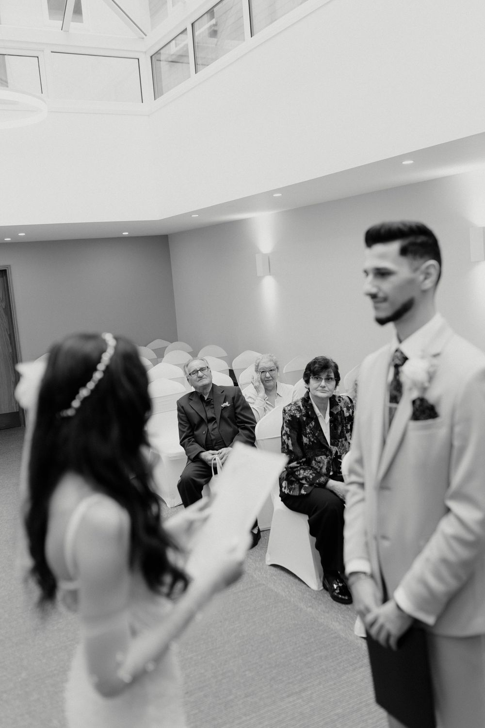 Wedding guests celebrate with a couple during an indoor reception ceremony.