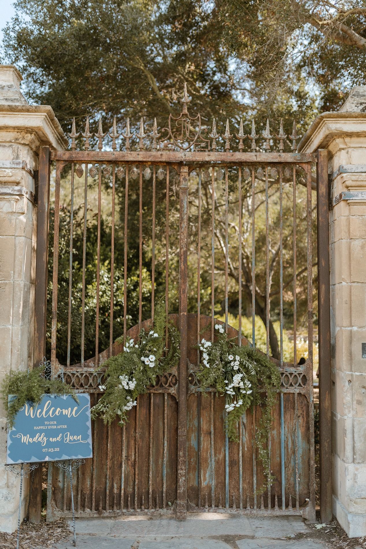 Rustic iron wedding gate adorned with white flowers and a welcome sign at The Havens Country Club.