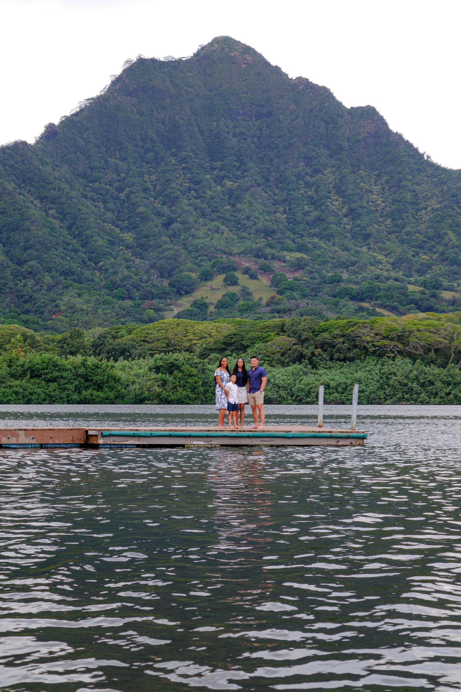 Scenic view of a dock extending into water with dramatic mountain landscape in Hawaii.