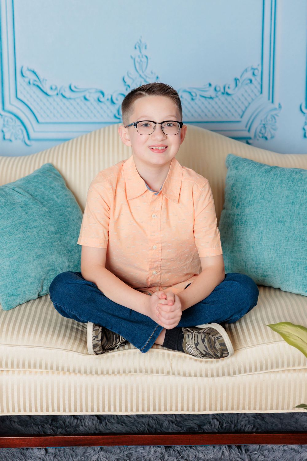 Someone in a peach colored shirt and jeans relaxes on a cream colored couch with turquoise pillows.