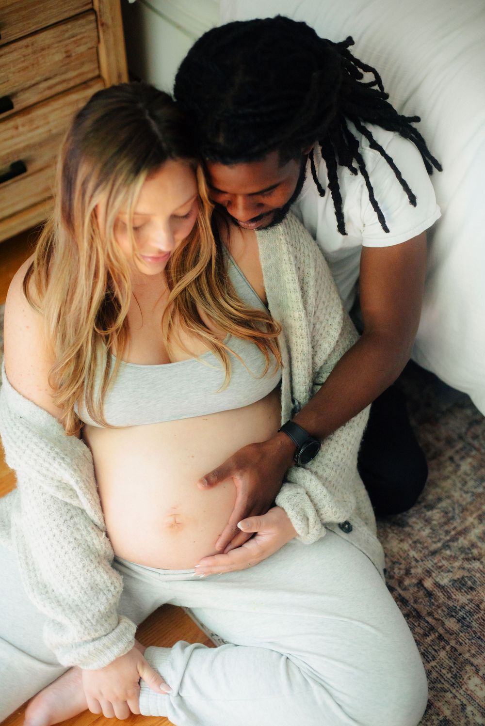 a biracial couple embracing a pregnant mamaś  belly in Marlborough MA