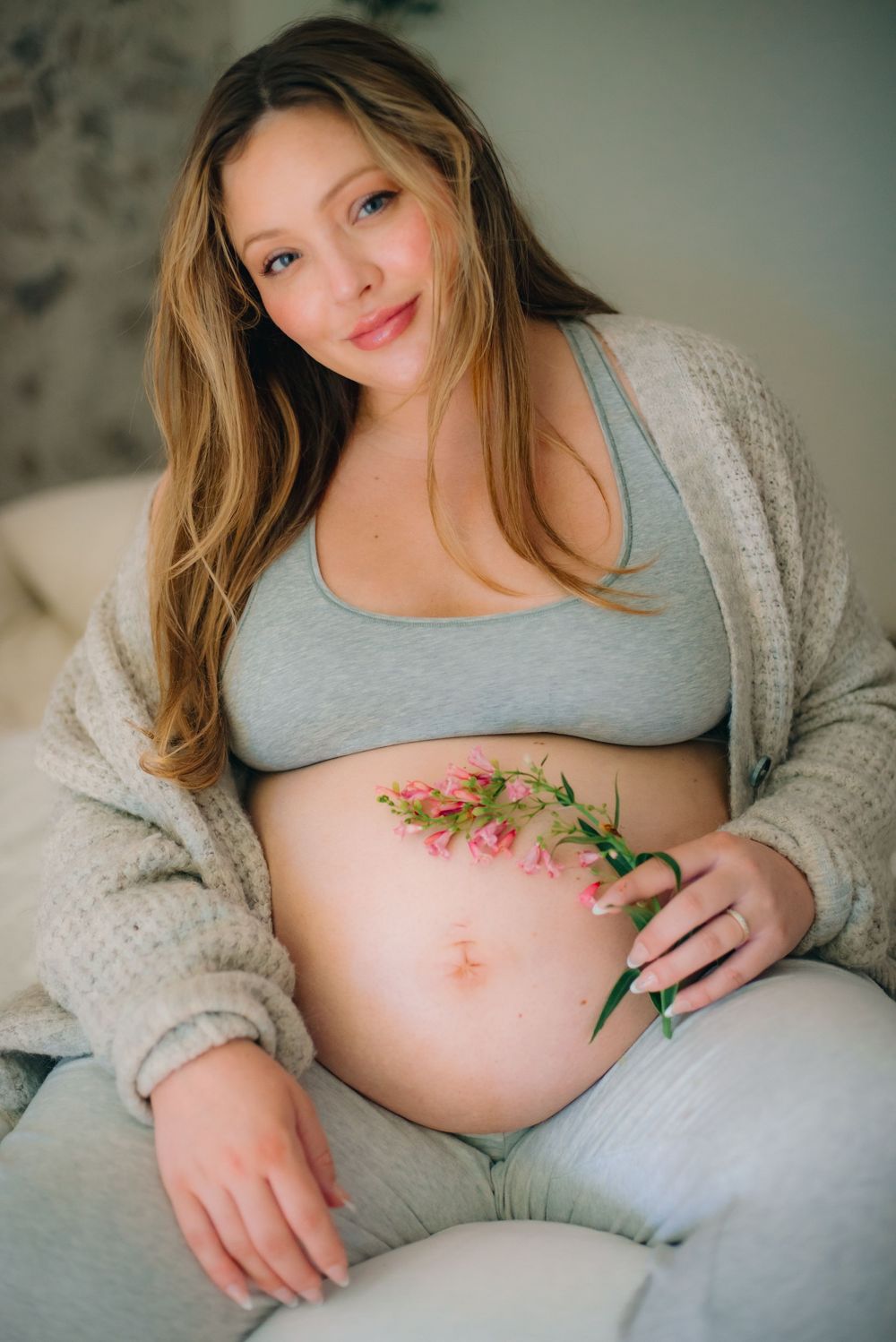 A pregnant mom displaying pink flowers over her belly. Pink flowers for a baby girl!