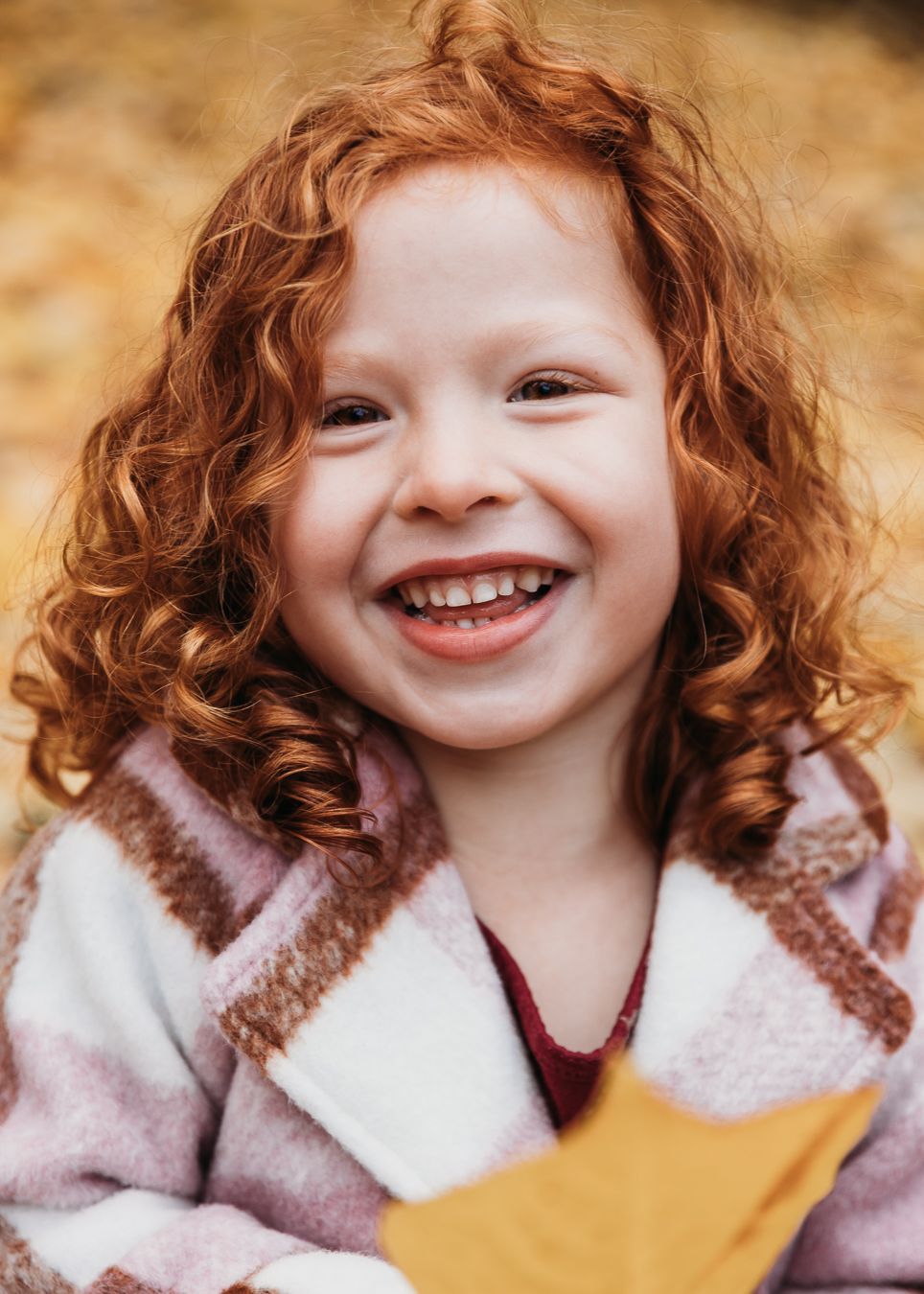 A series of five close-up photos showing a child with vibrant red curly hair and a warm smile wearing a fuzzy winter coat.