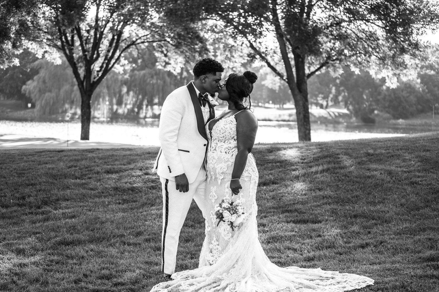 A romantic couple in white attire shares tender moments during their outdoor engagement photo session in a sunlit park.