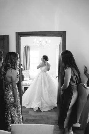 A sequence of black and white photos showing bridesmaids helping with a wedding dress in a sunlit room.
