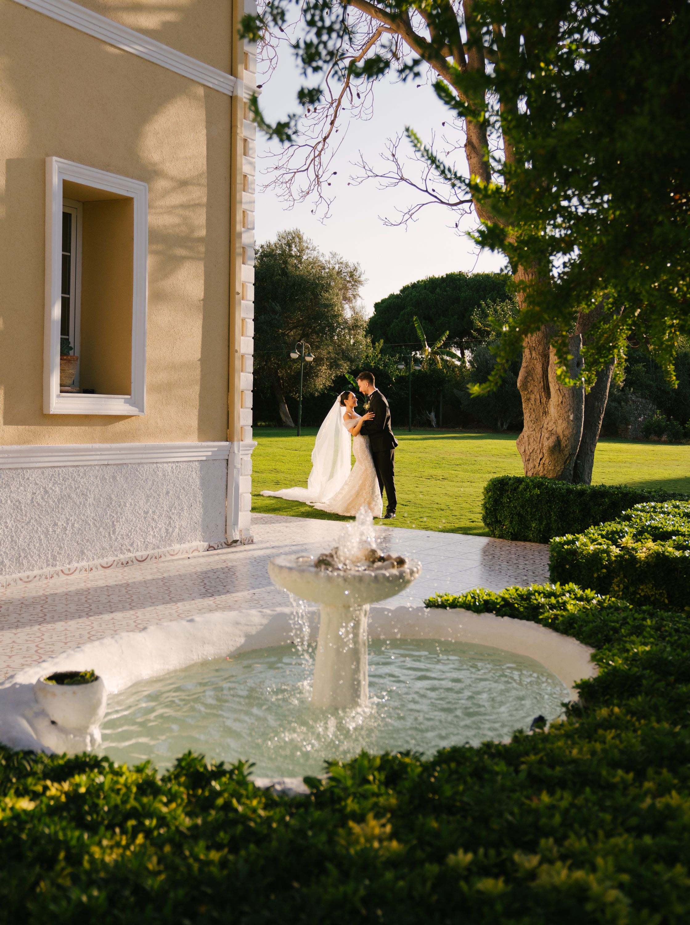 Couple poses for romantic photos near a decorative fountain at sunset.