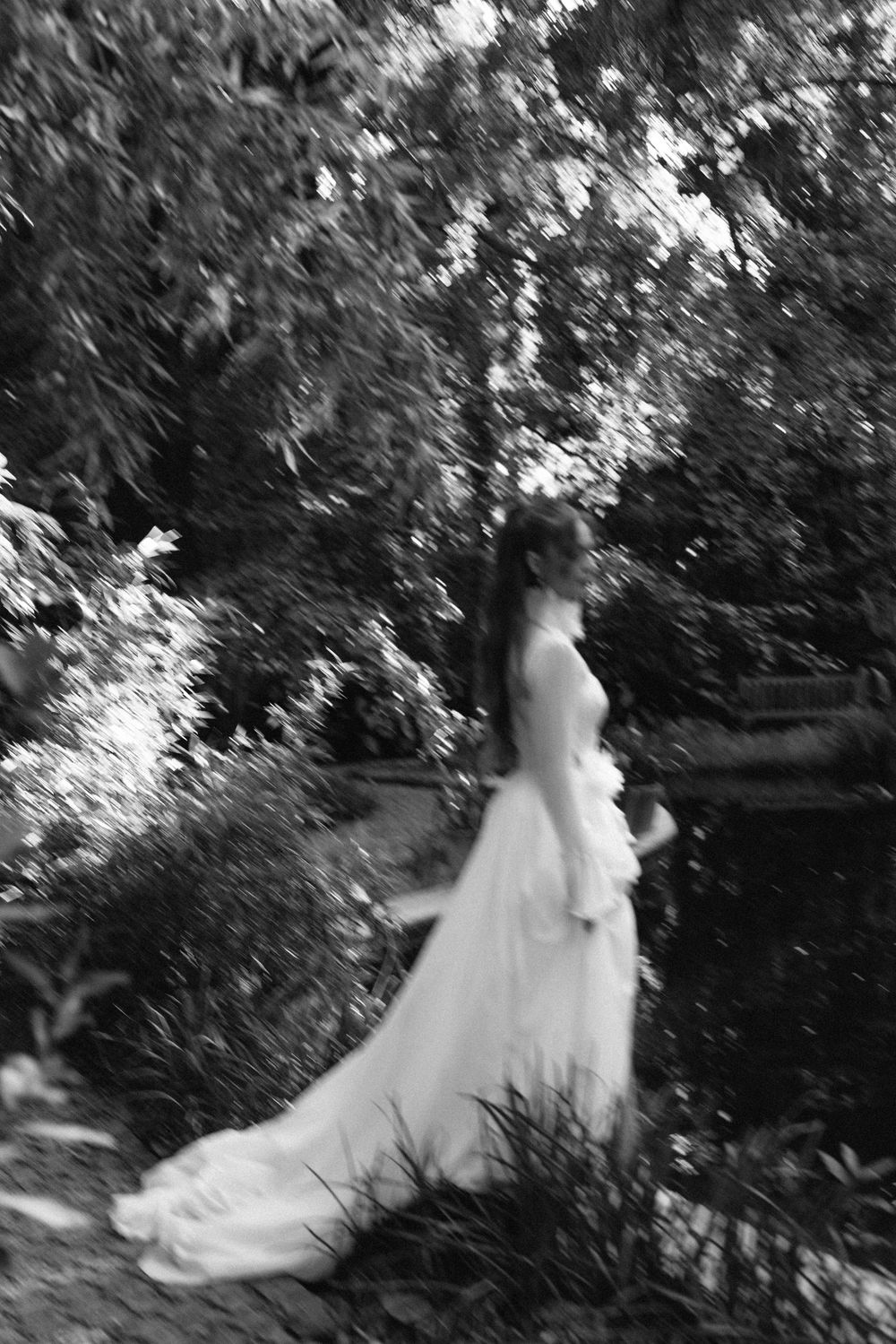 Artistic black and white sequence of bride spinning in garden setting.