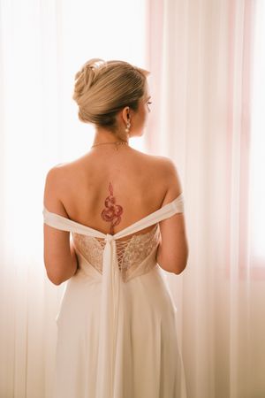 Back view of an elegant off-shoulder white wedding dress with delicate details against soft lighting.