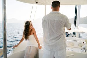 A panoramic view of people enjoying a sunny day on a luxury yacht sailing across blue ocean waters.