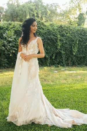 Elegant white wedding dress with lace details and flowing train photographed in a garden setting during golden hour.