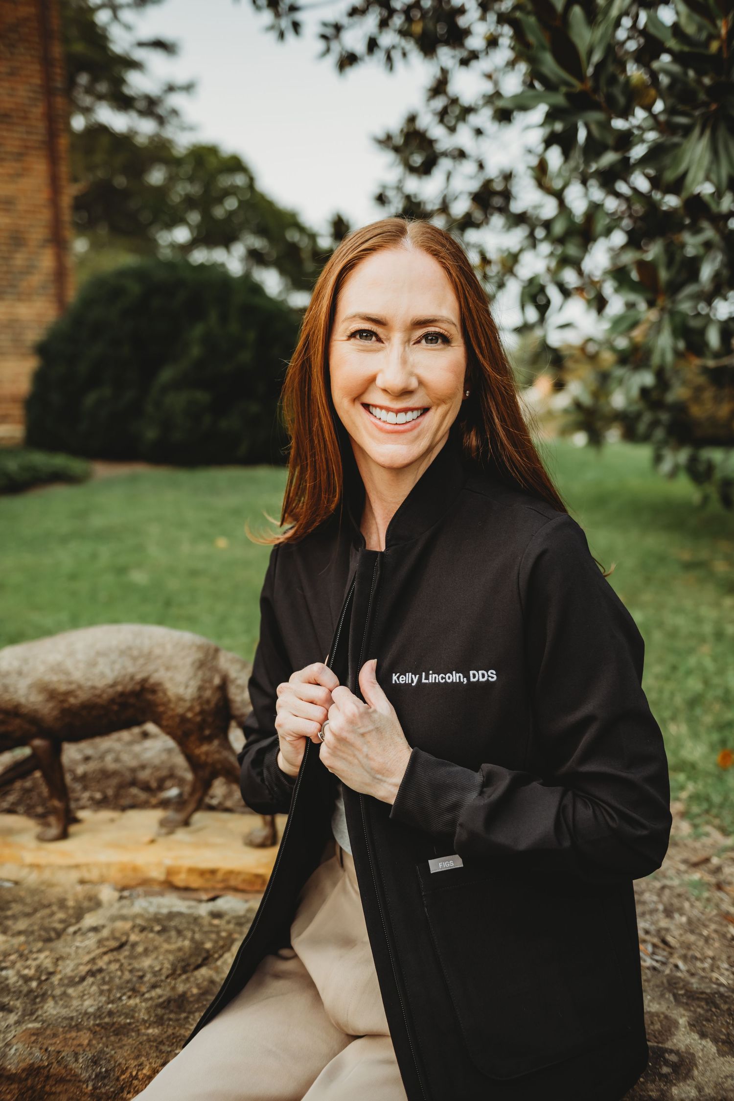A professional businesswoman smiling against a brick wall background.