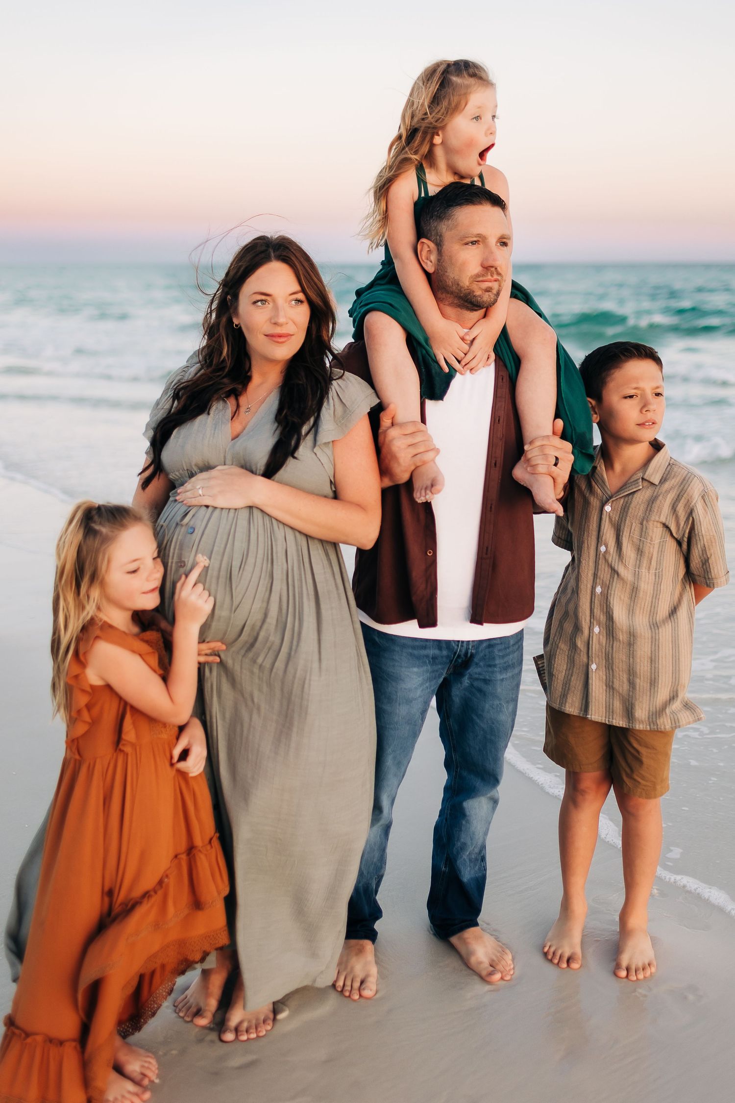 young family cuddling in navarre beach at sunset