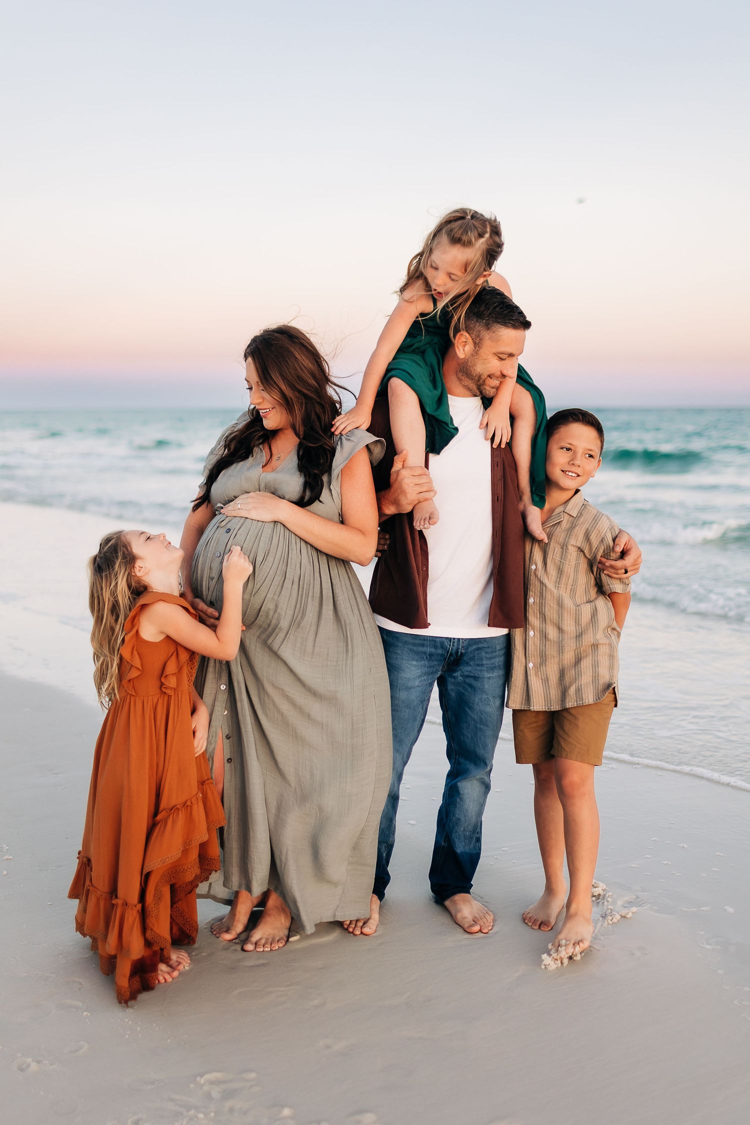 young family cuddling in navarre beach at sunset