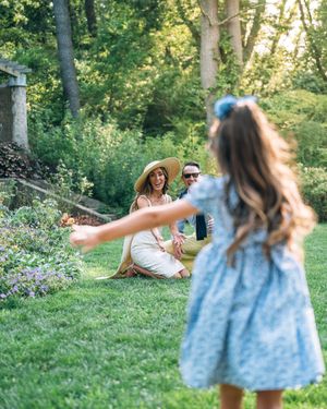 Young family enjoys a playful moment together on a lush garden lawn during golden hour.
