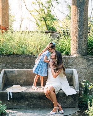 A tender moment between a parent and child sitting on a stone bench in a garden setting.