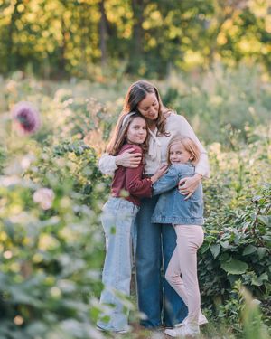 A family shares tender embraces while standing together in a lush garden setting during golden hour.