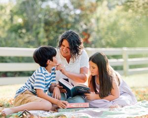 A family enjoys quality time together while relaxing on a picnic blanket in a sunny outdoor setting.