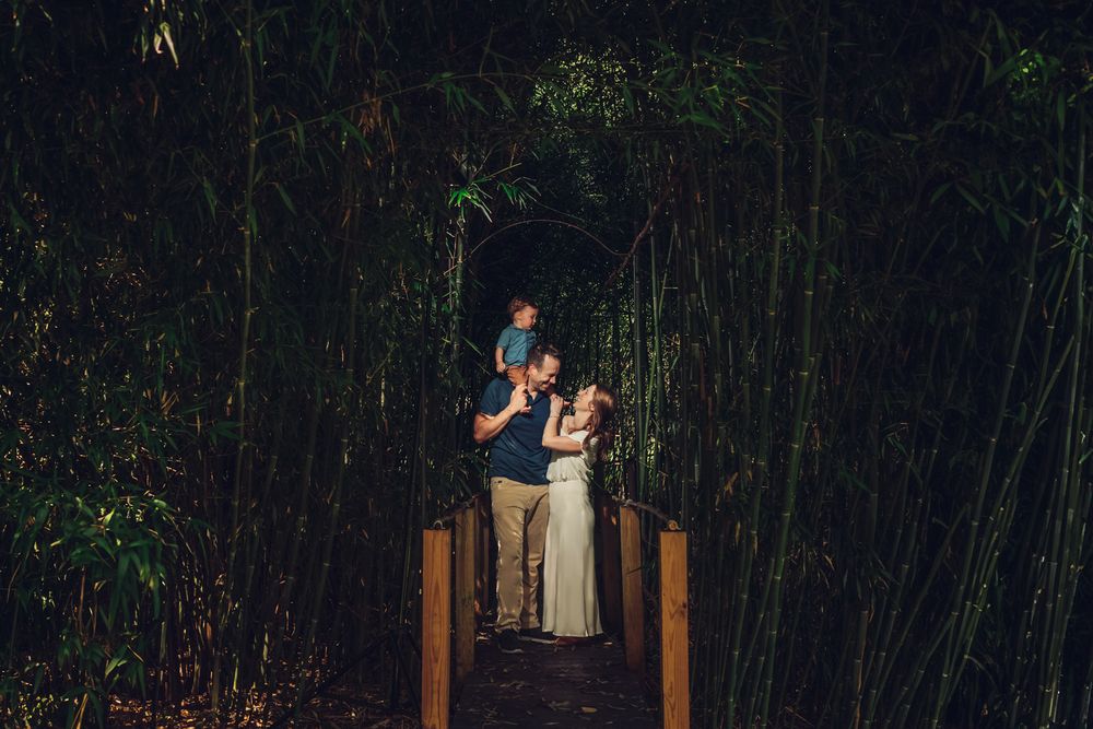 A couple embraces during an outdoor engagement photo session in a wooded forest setting at dusk.