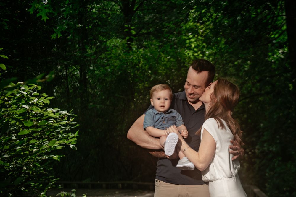 Family sharing tender moments together during an outdoor photoshoot in a wooded setting.