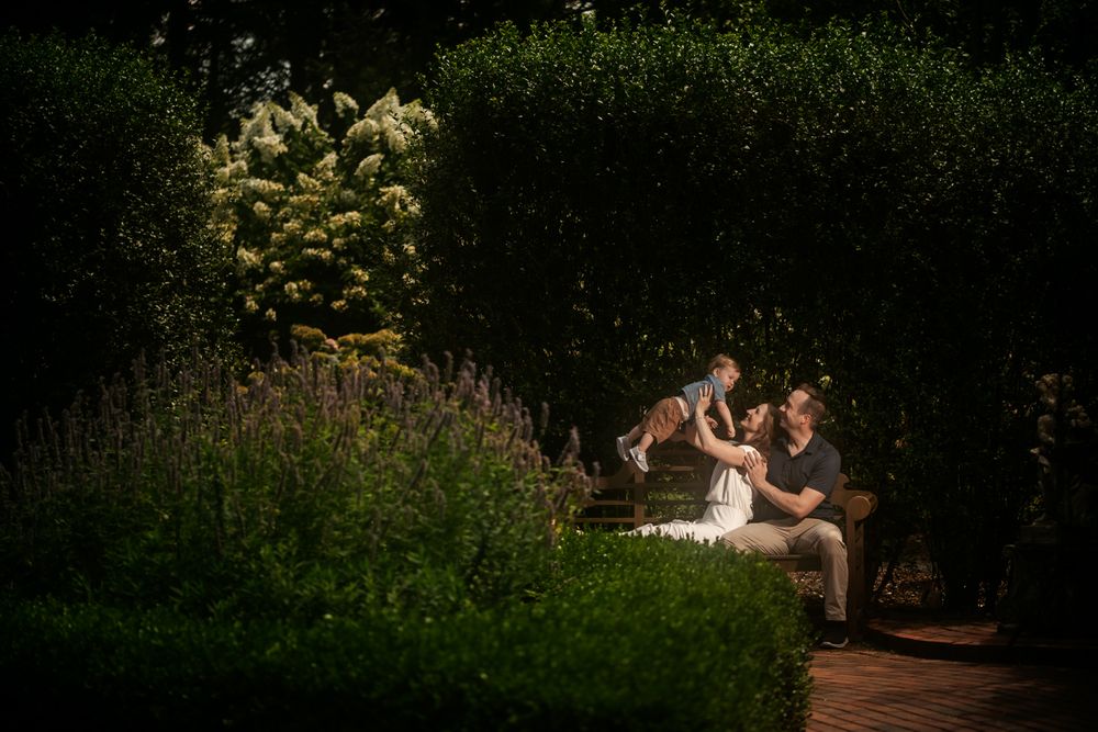 Couple embracing in a romantic outdoor photo session surrounded by lush greenery and natural lighting.