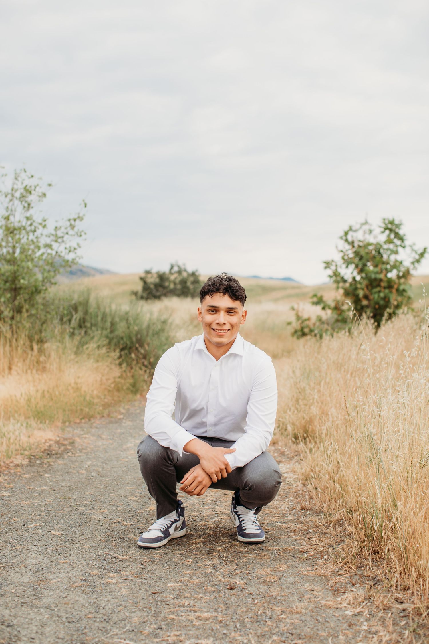 Portrait on dirt path with dry grass and shrubs in natural landscape setting.