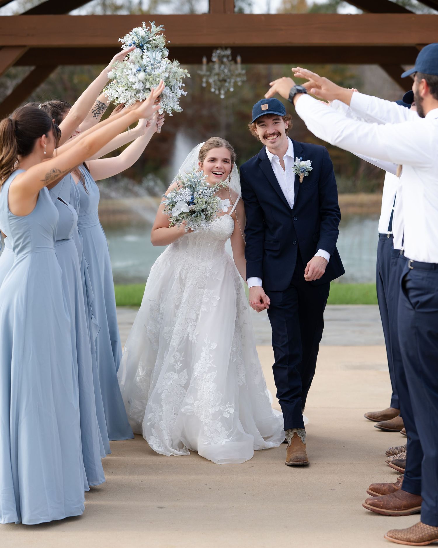 Newlywed couple shares romantic moment by lakeside dock in wedding attire during outdoor photo session.