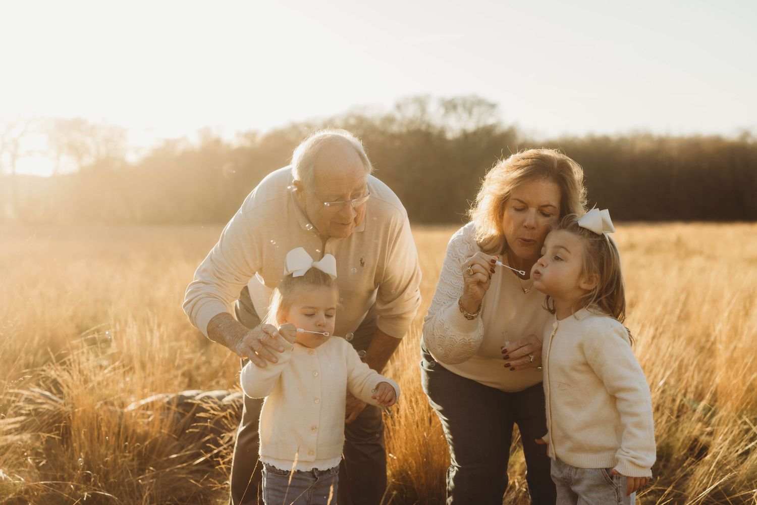 Family enjoying a warm sunset moment together in a golden wheat field during autumn.