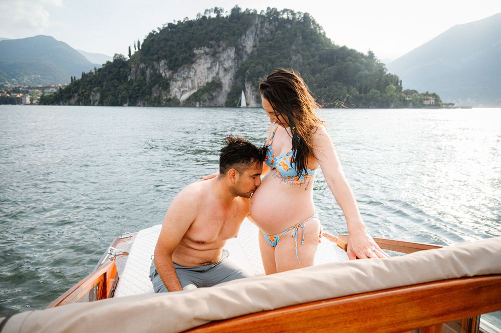 Couple relaxing on a wooden boat with scenic mountain lake views in the background.