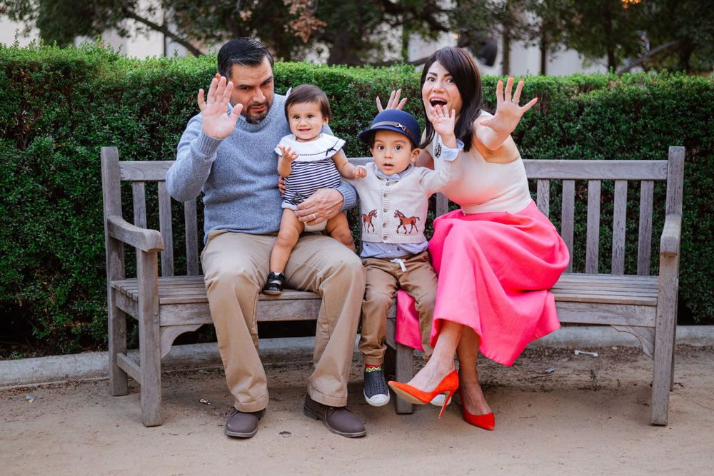 Family members sitting together on wooden park benches in garden setting.