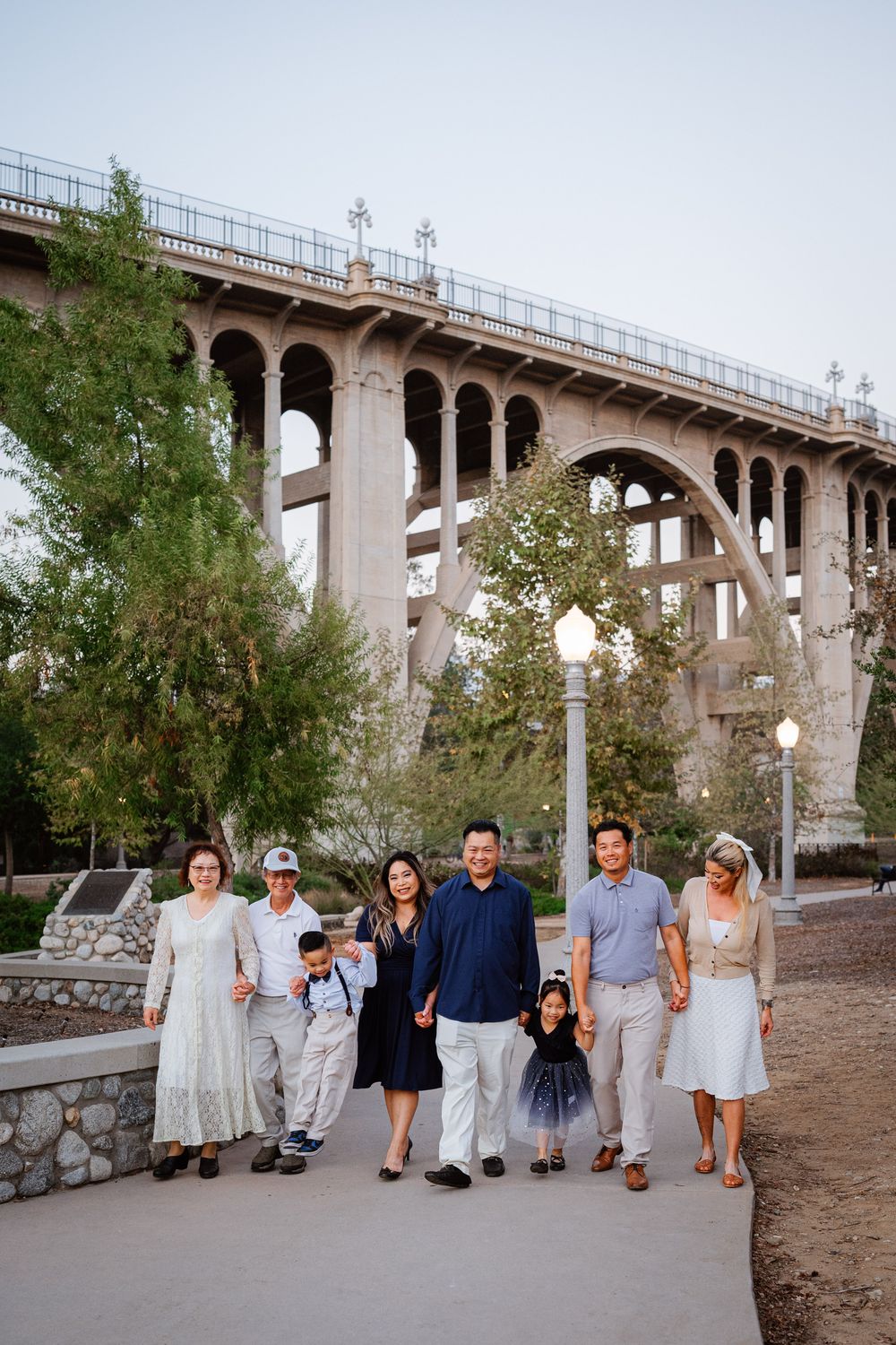 Family group walking together beneath historic concrete bridge structure.