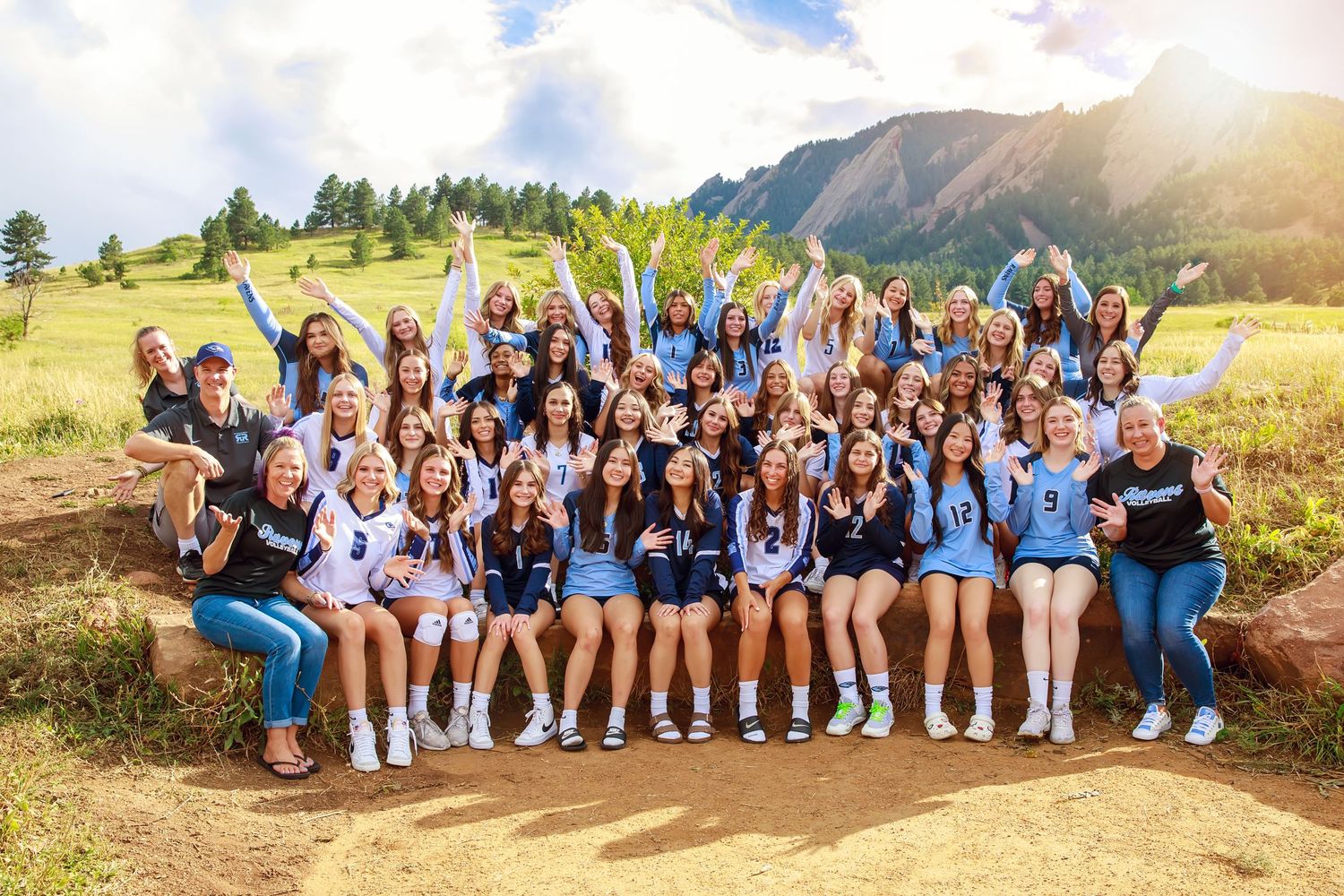 High school pom squad in purple uniforms poses on wooden bridge for team photo.