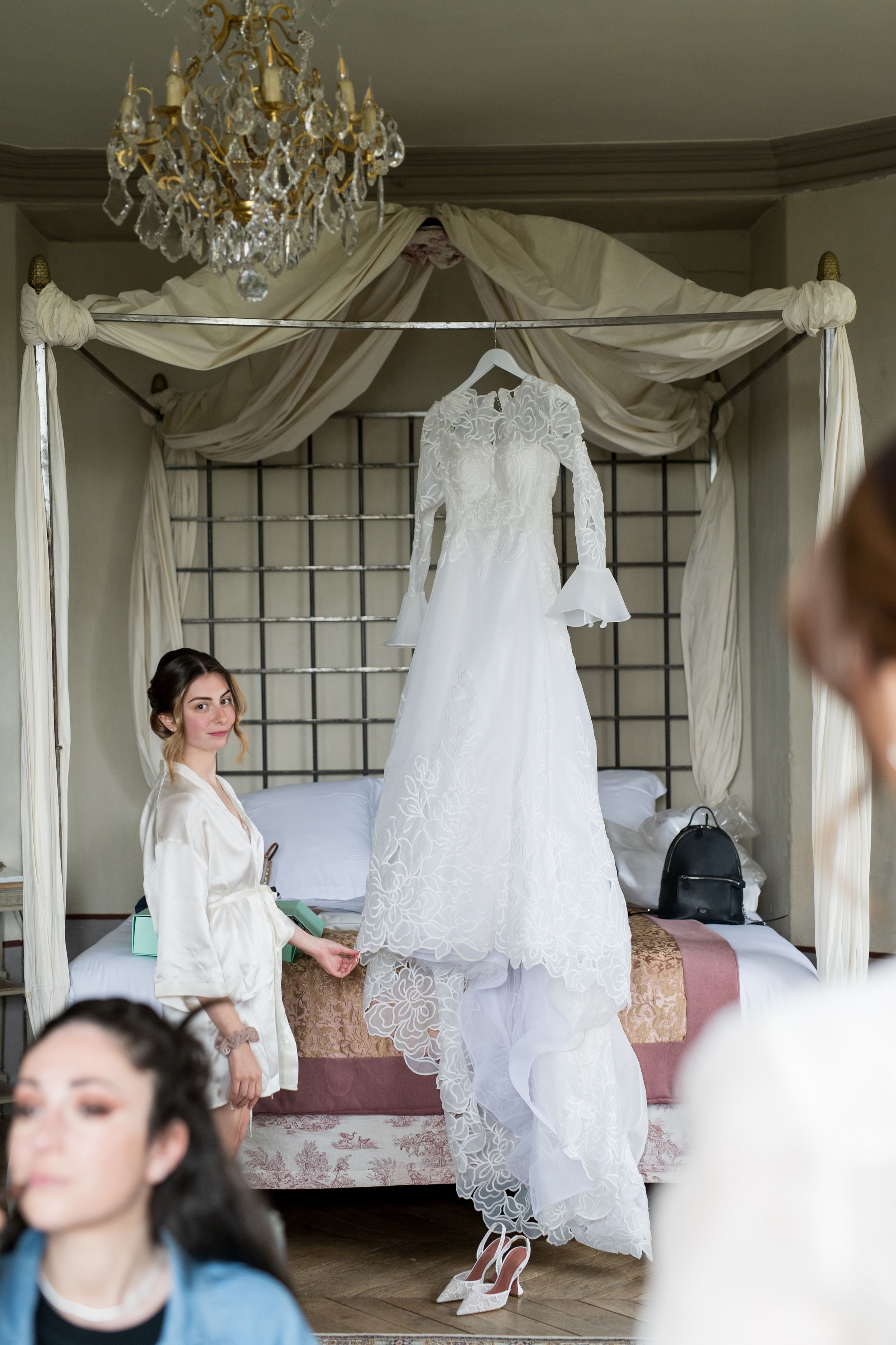 Robe de mariée suspendue dans une chambre décorée, scène de préparatifs douce et lumineuse.