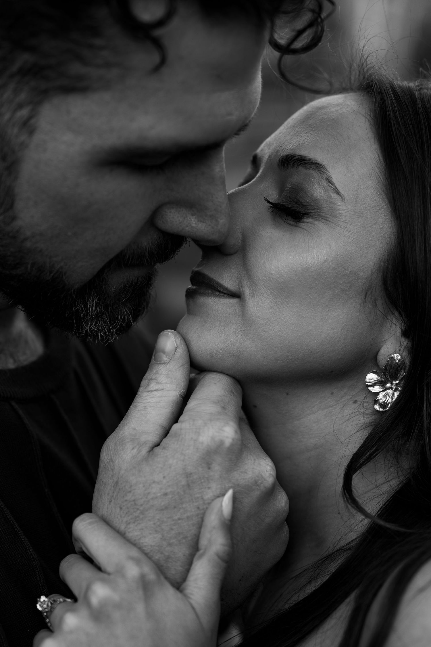 Black and white close-up of a romantic couple about to kiss, man tenderly holding woman's face.