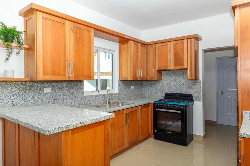 Modern kitchen with honey oak cabinets, granite countertops, mosaic tile backsplash, and black gas stove.