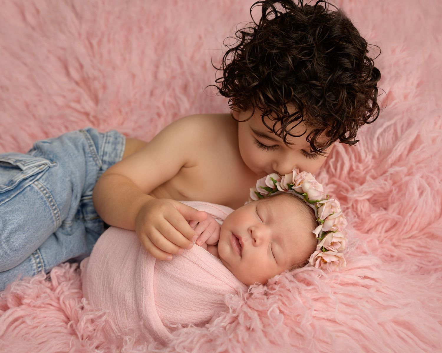 Older brother gently kisses his newborn sister during a sibling newborn photography session in Zephyrhills, Florida.