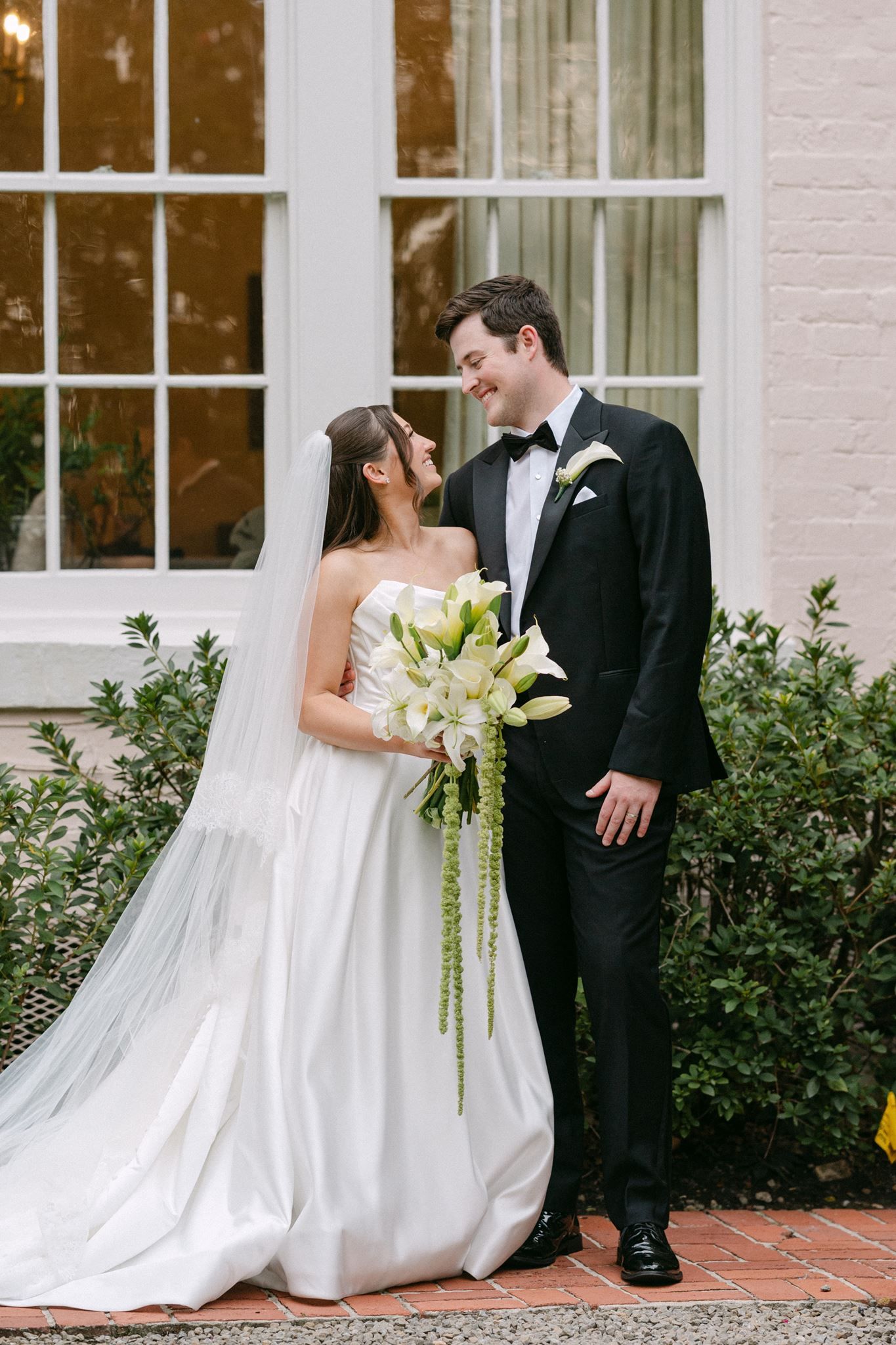 Bride and groom sharing a smile in front of River Oaks Garden Club.
