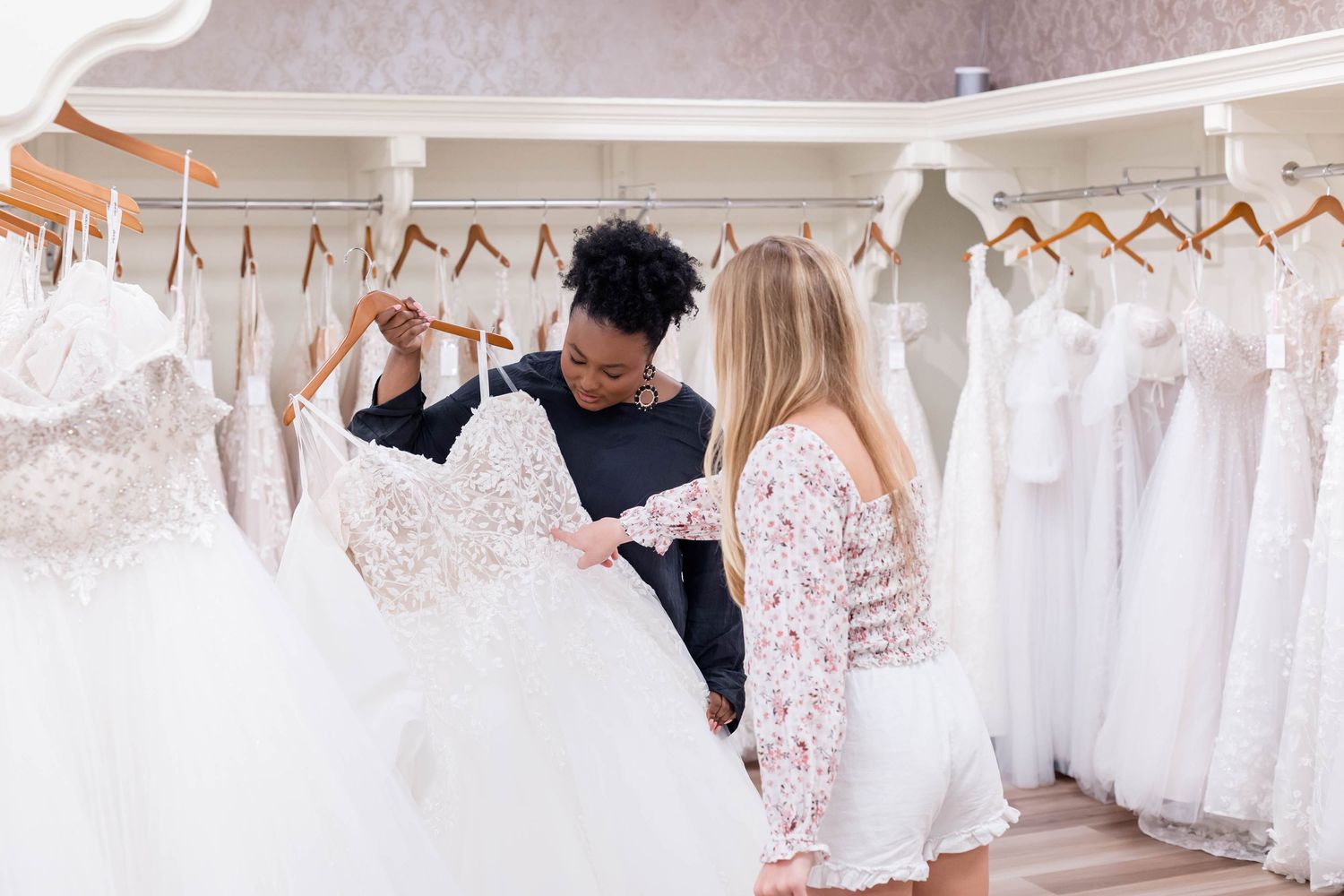 bridal stylist shows customer a dress at a bridal shop.