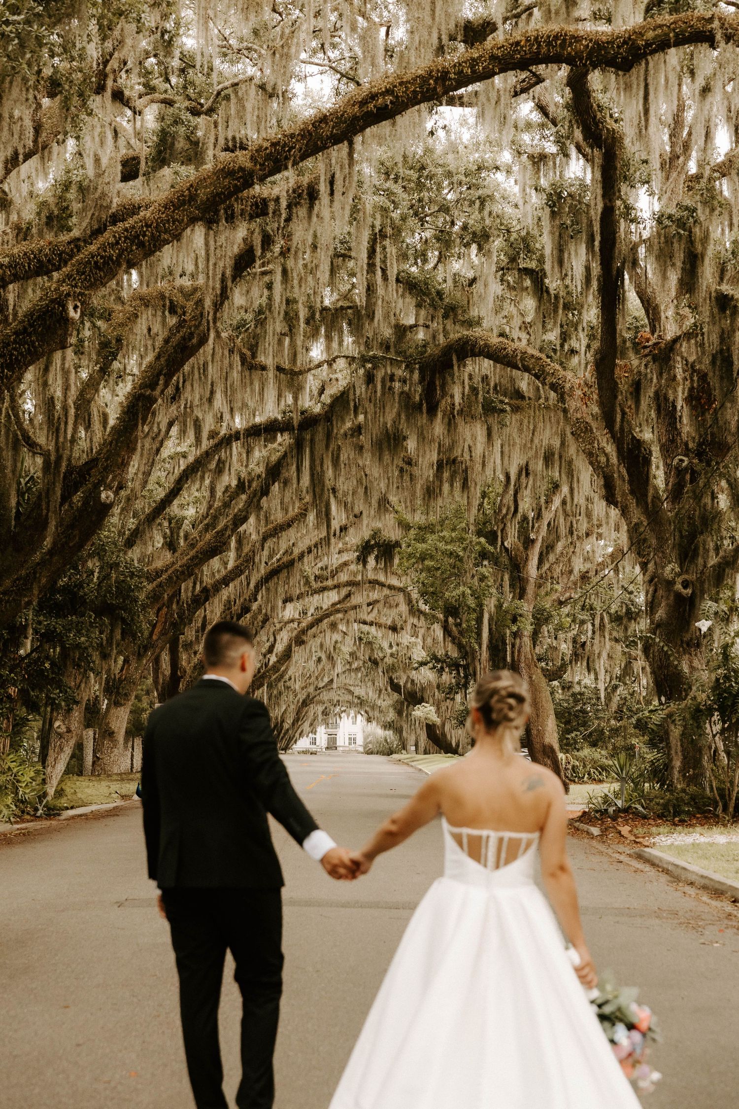 Bride and groom pose on stone steps before an ornate classical building with arched colonnade on their wedding day.