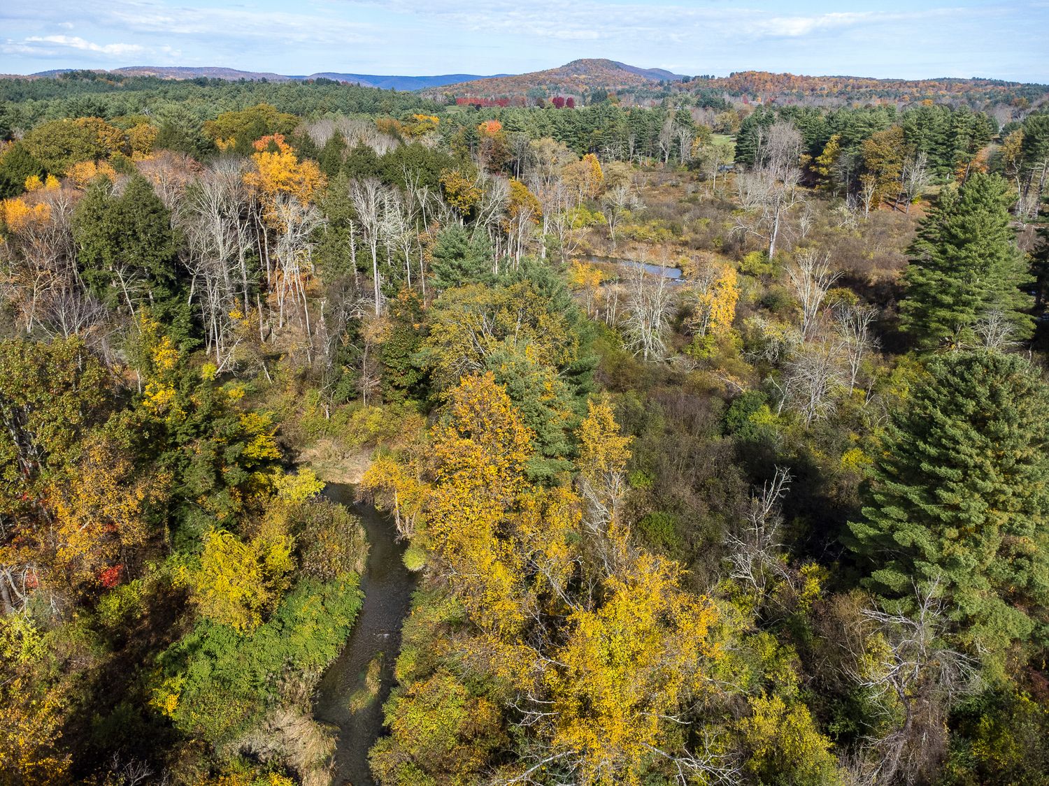 Aerial autumn view of a New England town with colorful fall foliage and historic church steeple.