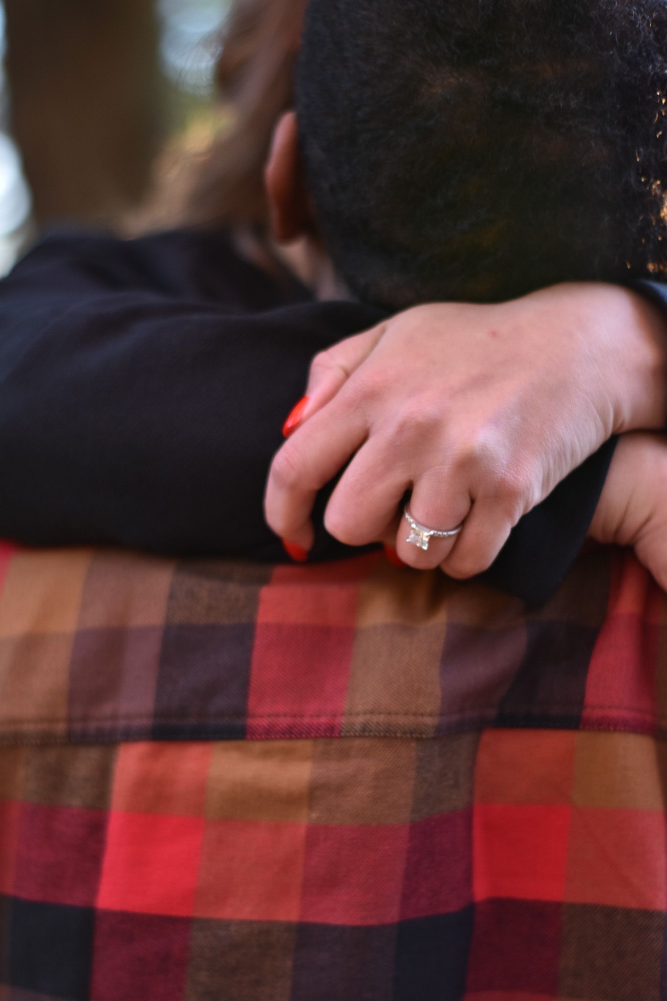 A couple lovingly gazes at their newborn baby wrapped in a blanket with a yellow bow headband near a sunlit window.
